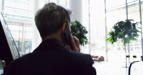 Businesswoman talking on mobile phone in the lobby at office 4k