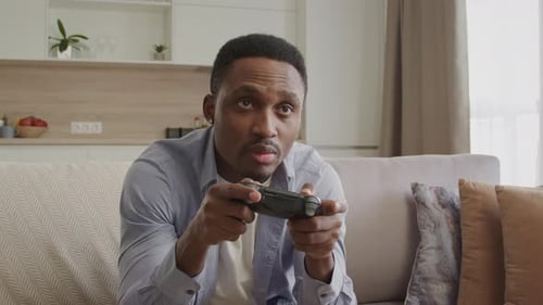 Man Plays Video Games on Couch at Home