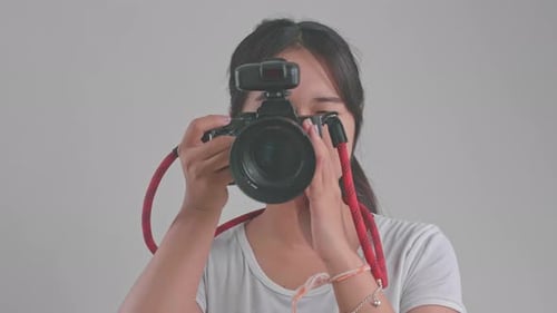 Young Asian Female Photographer Standing And Taking Photos In Studio
