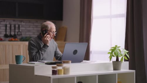 Old Businessman is Working From His Home Office in Apartment Calling By Mobile Phone and Using