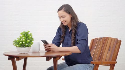 Woman Using Smartphone at Wooden Table Indoors