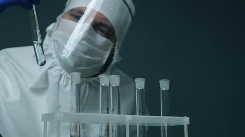 Scientist analyzing test tubes wearing protective suit