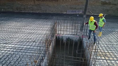 Workers Pouring Cement Into Foundation at Construction Site