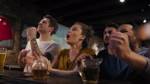 Group of friends cheering to soccer match in the pub. Shot with RED helium camera in 8K.