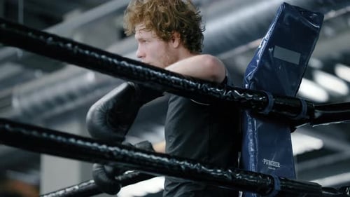 Distressed Fighter Standing in Fitness Center. Kickboxer Leaning on Ropes at Gym