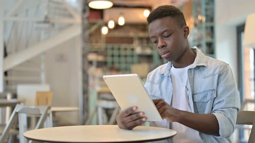 Cheerful African Man working on Tablet in Cafe