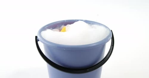 Cleaning sponge falling in to bucket of soap suds