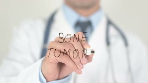 Doctor Writing About Bone Tumors on Glass