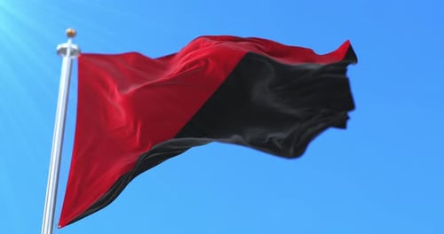 Waving Red and Black Flag Loop Against Blue Sky