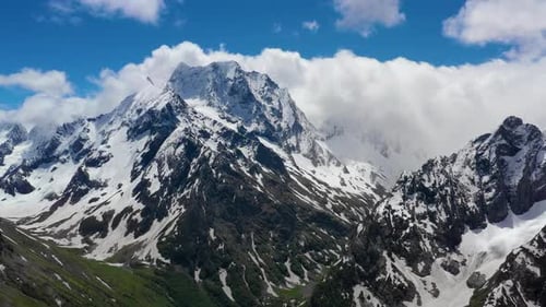 Air Flight Through Mountain Clouds Over Beautiful Snowcapped Peaks of Mountains and Glaciers