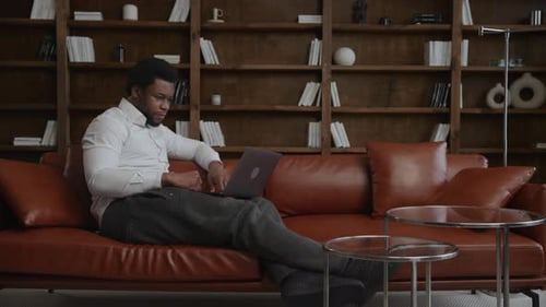 Young Adult Africanamerican Enterpreneur Having a Conference Call on His Laptop