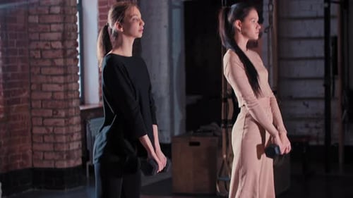 Two Women Training Together in the Gym Squatting with a Dumbbell