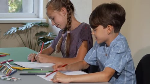 Children Drawing Together at Table Indoors