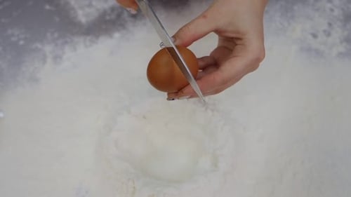 Cracking An Egg Into Flour For Baking