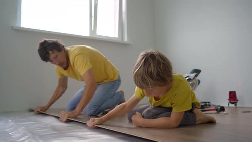 Father and Child Installing Wood Flooring Together