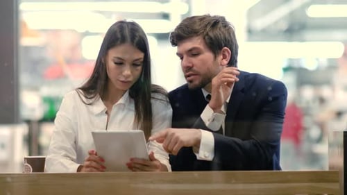Business Couple Using a Tablet While They Have a Coffee Break