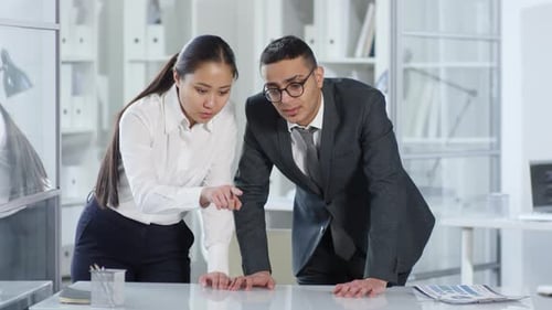 Asian Woman and Arab Man Looking at Invisible AR Touchscreen in Office