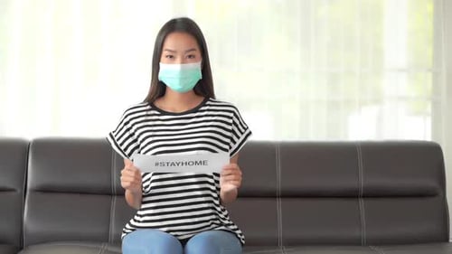 Woman Wearing a Mask Holds Stay Home Sign