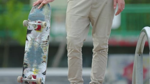 Young Adult Holds Skateboard at Skate Park