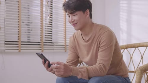 Young Man Video Chatting on Smartphone Indoors