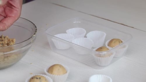 Eine Frau rollt Bällchen mit Erdnussbutter, Schokolade und Kokosmehl.