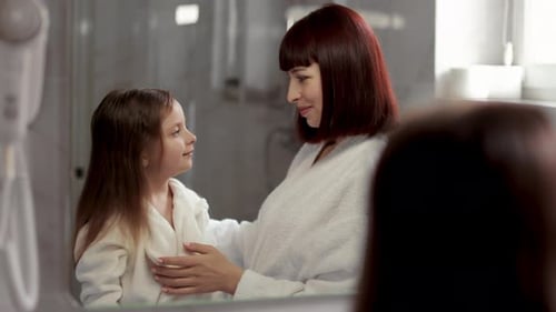 Loving Mother Brushing Daughter's Hair in Bathroom