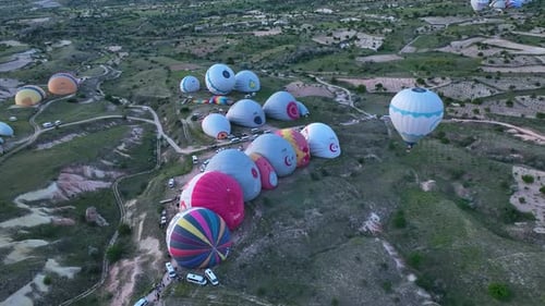Hot air balloons fly over the mountainous landscape of Cappadocia, Turkey.