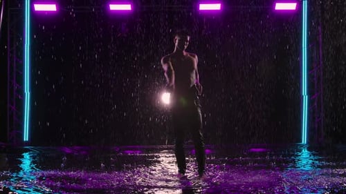 Hombre mojado bailando un sensual ballet moderno sobre la superficie del agua bajo la lluvia