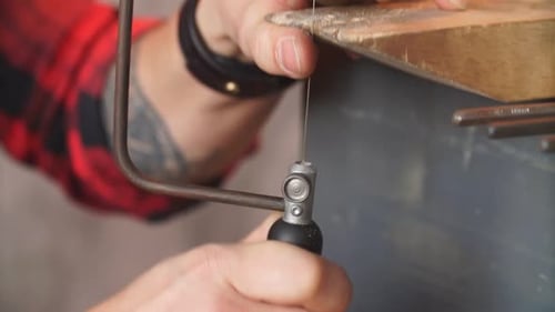 Young Man Learning To Work with Fret Saw. Handsome Guy Using the Tool for Accurate Cutting