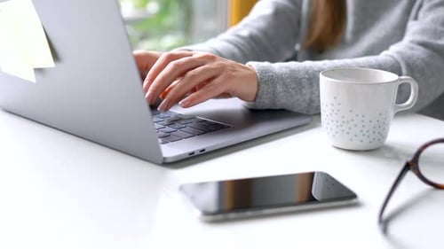 Beautiful Woman Sitting at Home Office and Working on a Laptop