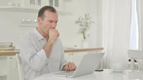 Man Coughs While Using Laptop at Home
