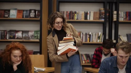 Ralentissement d'une jeune fille en veste brune et lunettes marchant dans une rangée avec une pile de livres qu'elle a emportés