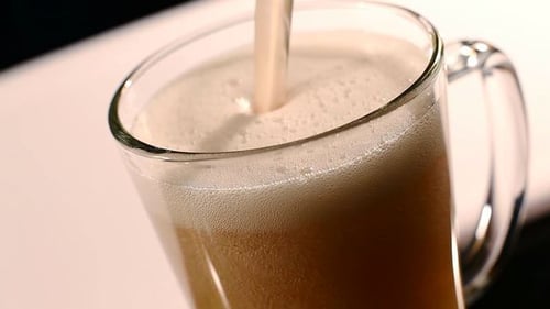Foamy Beverage Being Poured Into Glass Mug