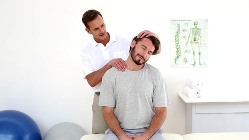 Chiropractor Adjusts Neck of Seated Man in Clinic