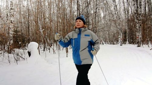Woman Walking With Ski Poles in Snowy Forest