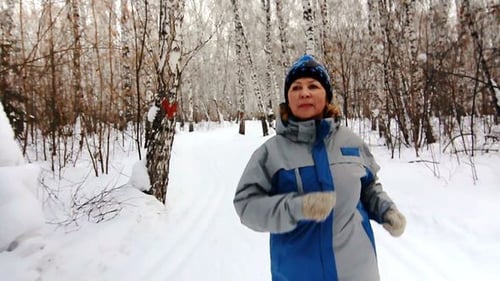 Woman Jogging in a Snowy Birch Tree Forest