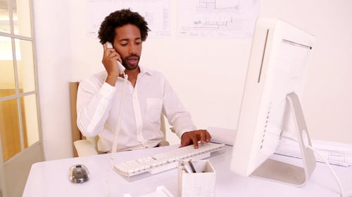 Man Talking on Phone While Working at Computer