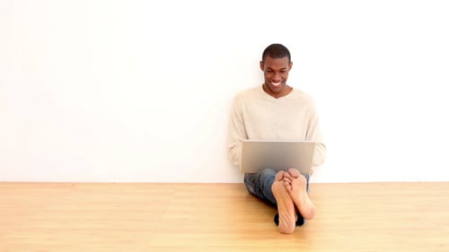 Smiling Adult Using Laptop on Floor