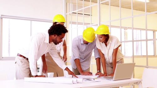 Team of Architects Collaborating Over Blueprints in Office