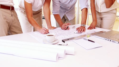 Team Collaborating on Blueprints in Modern Workplace