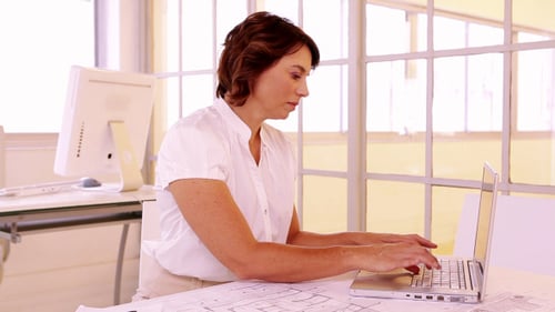 Woman Working at a Desk Typing on Laptop