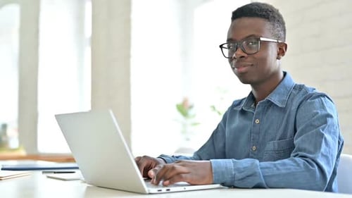 Young Man Working on Laptop in Bright Office