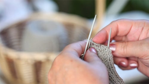 Woman Knitting with Needles and Grey Yarn