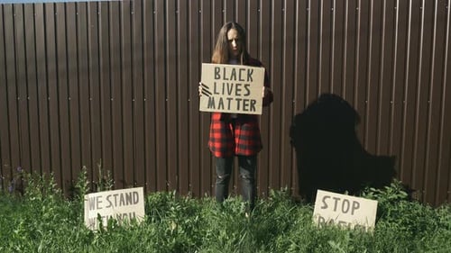 Young Adult Holding a Protest Sign Outdoors