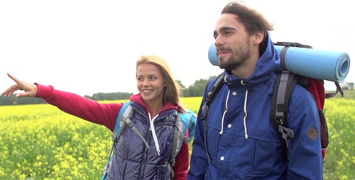 Couple Hiking Through Sunny Rural Field
