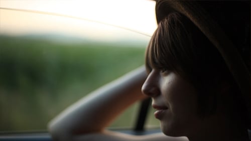 Young Woman Enjoying Car Ride at Sunset