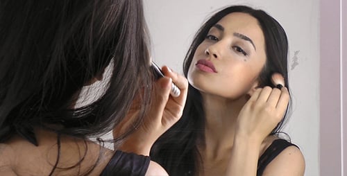 Woman Applying Makeup in the Mirror
