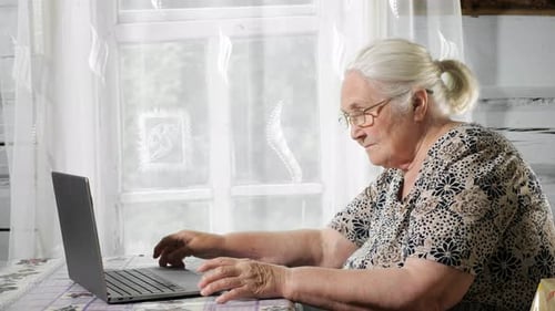 Senior Woman Using Laptop At Table Indoors