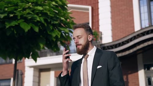 Bearded Man in Suit Talking on Phone Outdoors