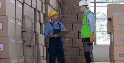 Warehouse Workers Discuss Inventory Checking Boxes